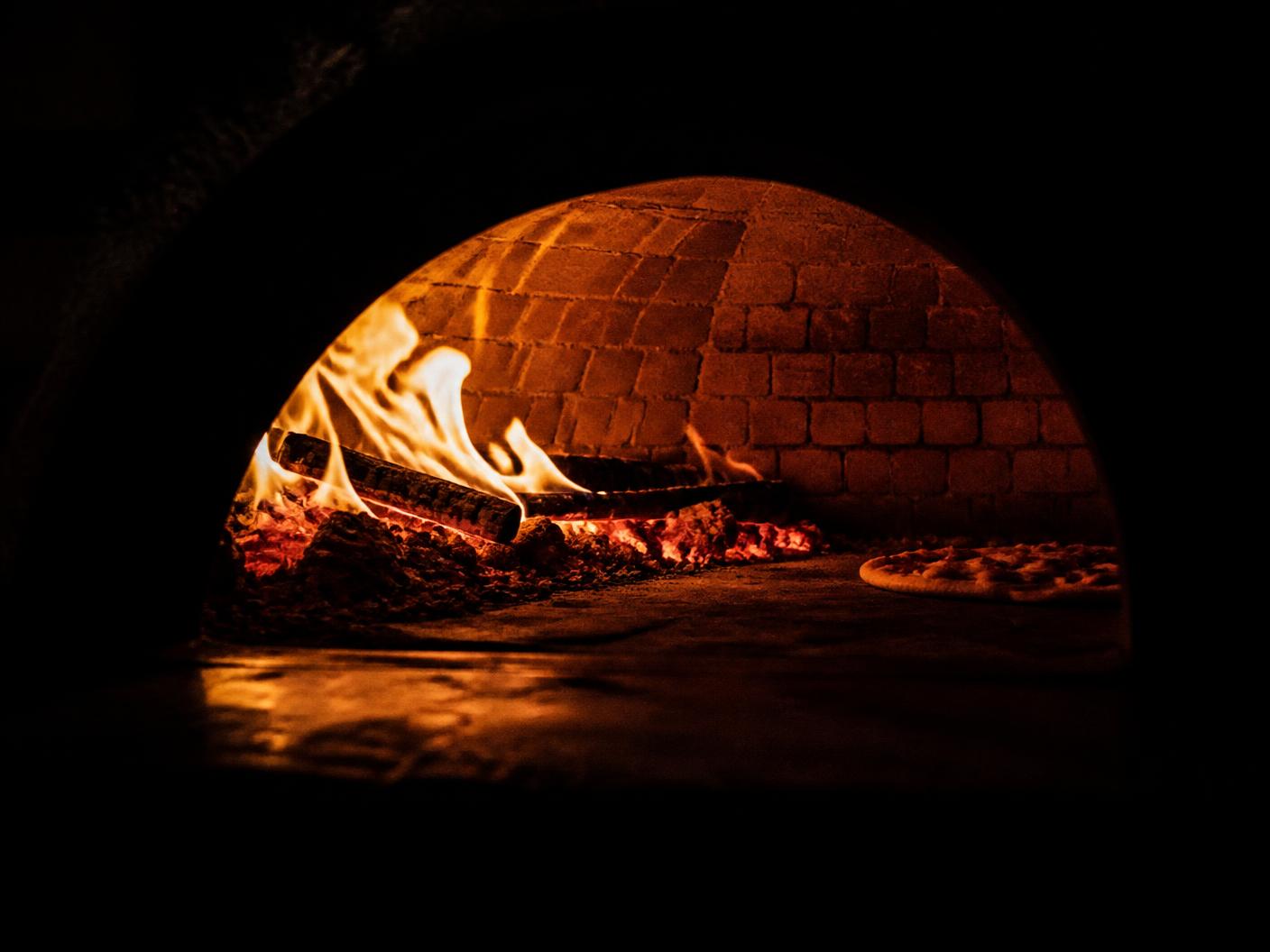 Flames and embers burning inside the brick dome of a wood-fired oven